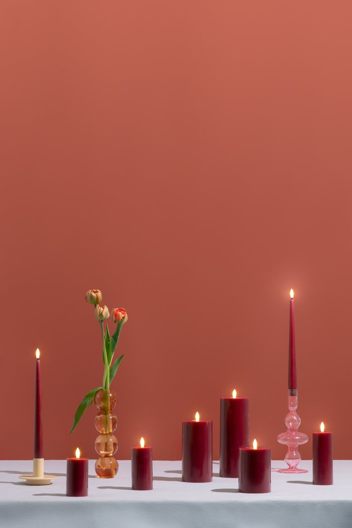 Bougie pilier LED effet cire fondue rouge canneberge, plusieurs tailles réunies sur une table