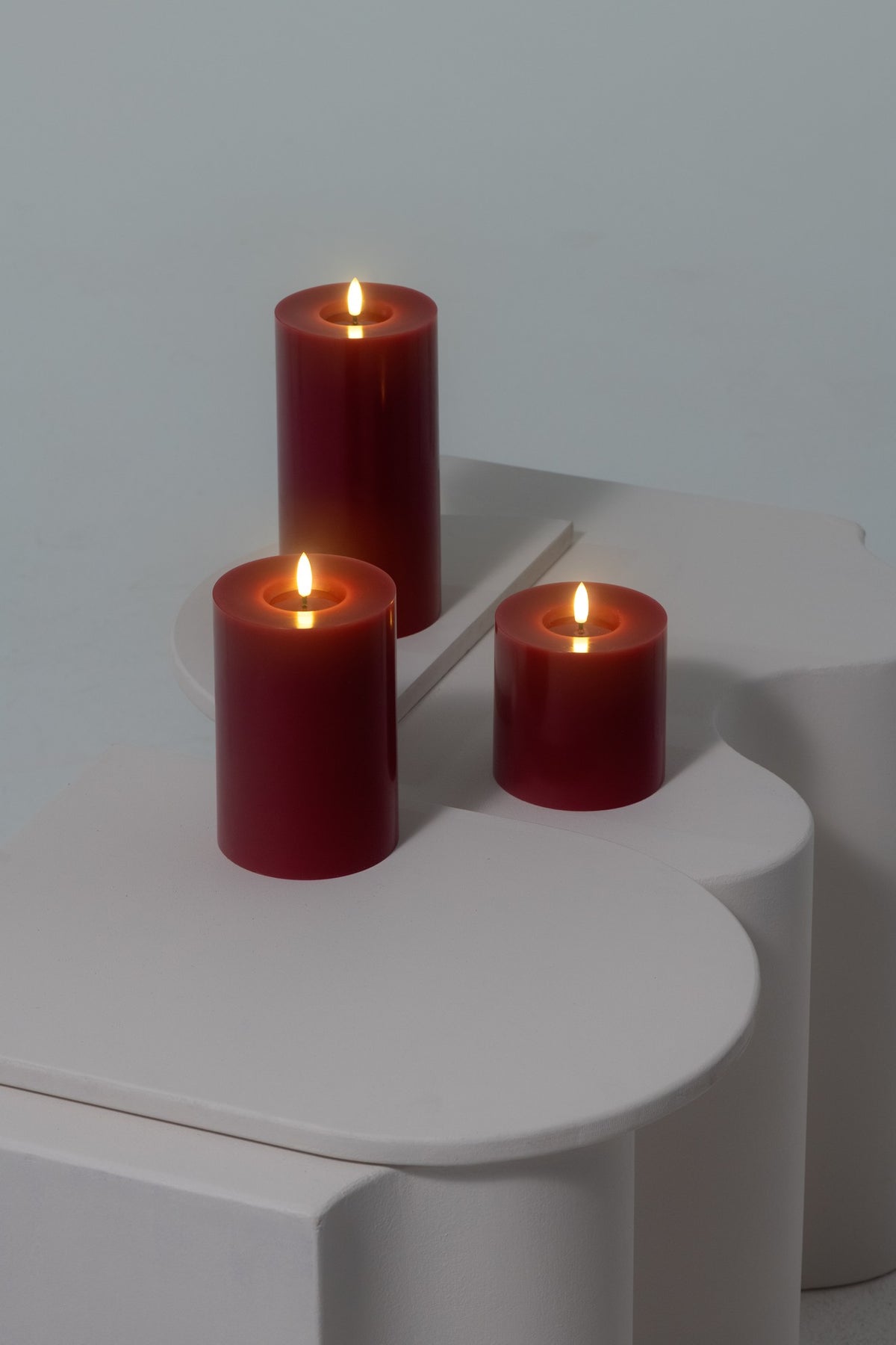 Bougie pilier LED effet cire fondue rouge canneberge, plusieurs tailles réunies sur une table, vue 2