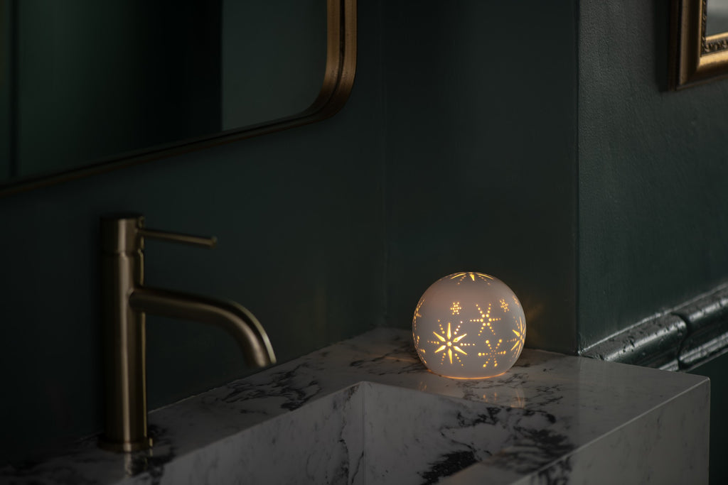 Photophore dôme en céramique blanche ajourée, avec une bougie chauffe-plat LED allumée, vue 2