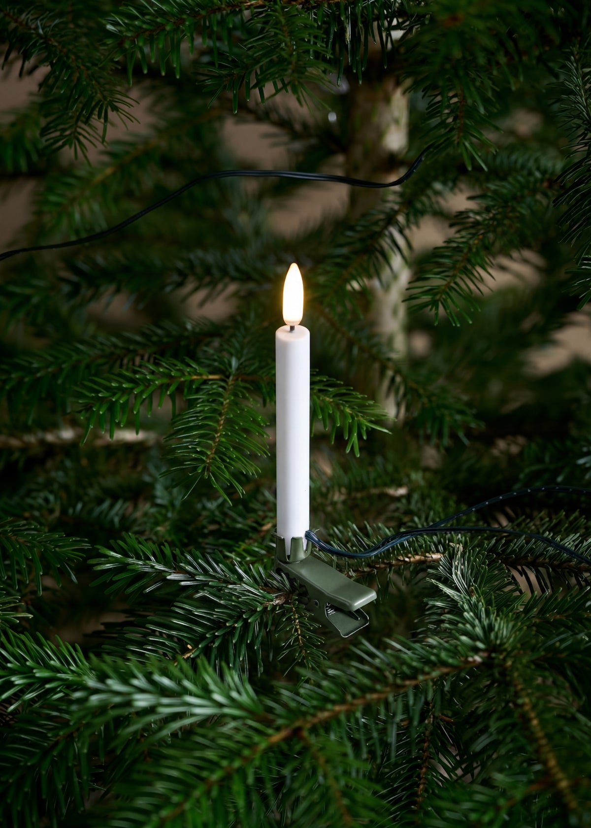 Mini bougies LED fixées par des clips métal sur un sapin de Noël